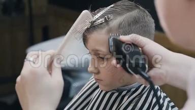 理发店里的理发师和可爱的客户孩子。 理发店使用修剪机和梳子。 漂亮可爱的孩子